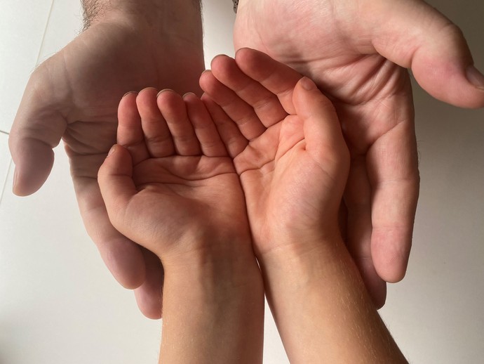 Das Bild zeigt große Hände die kleine Hände schützen. Quelle: Brown