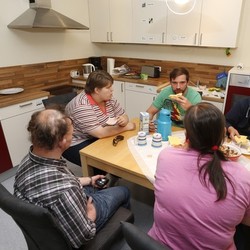 Auf dem Bild sind mehrere Menschen zu sehen, die gemeinsam an einem Tisch essen.